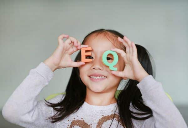 A sorridente colocando 2 letras do alfabeto frente aos olhos: 1 verde e outra vermelha. Testando o daltonismo.