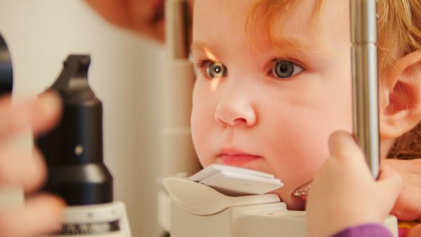 Criança, com mais ou menos 2 anos, realizando exames oftalmológicos para detectar coloboma.
