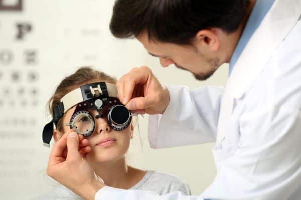 Oftalmologista realizando exame oftalmológico e menina pequena.
