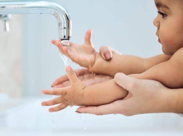Mamãe incentivando seu bebê a lavar as mãos após brincadeiras.