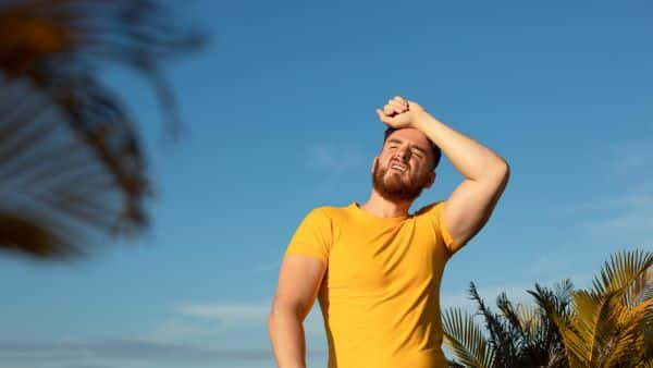 Homem ao ar livre sofrendo as ações das altas temperaturas do verão. Conceito de doenças sazonais.