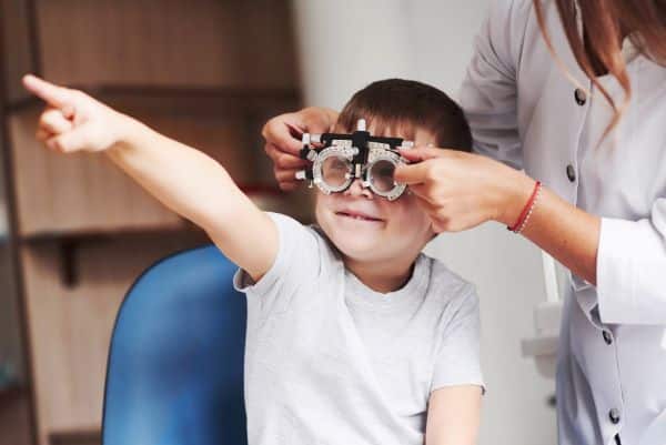 Menininho realiza teste de acuidade visual em consultório oftalmológico.