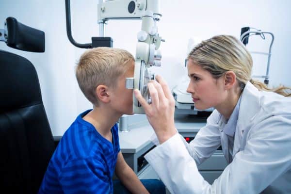 Menino de uns 11 anos realizando exame ocular para detectar ceratocone. 