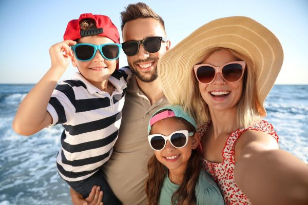 Família feliz tirando selfie na praia, perto do mar , durante as férias de verão.