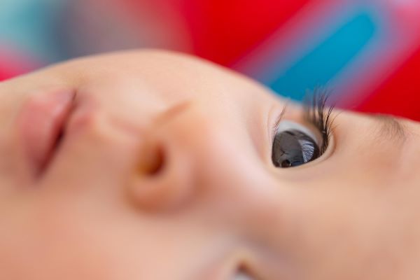 Close-up do rosto de um bebê com olhos escuros.