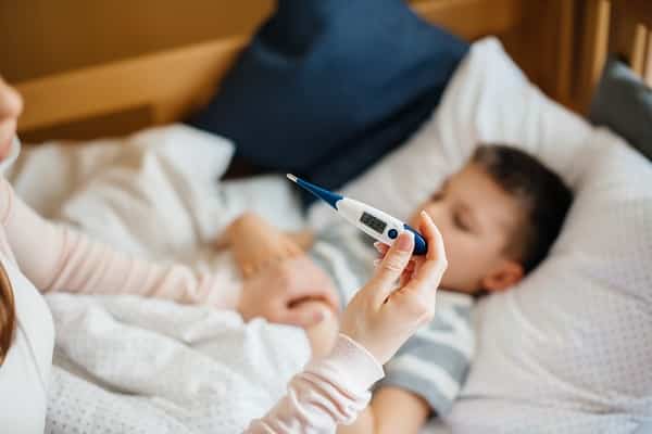 Uma mãe cuidando do filho que está doente. Ela mede a temperatura do menino.