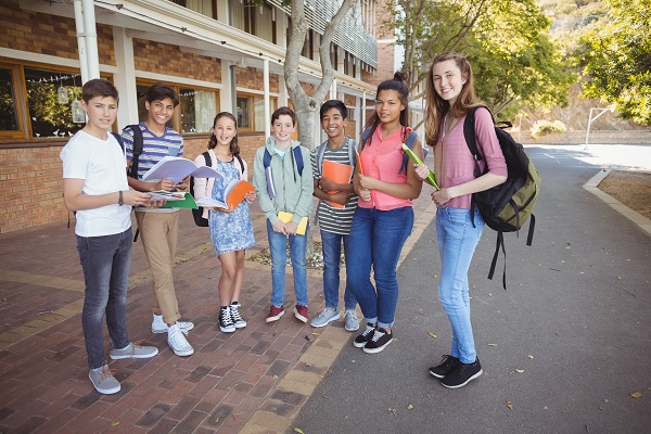 Grupo de adolescentes felizes frente ao prédio da escola.